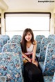 A young woman sitting on a train with a suitcase.